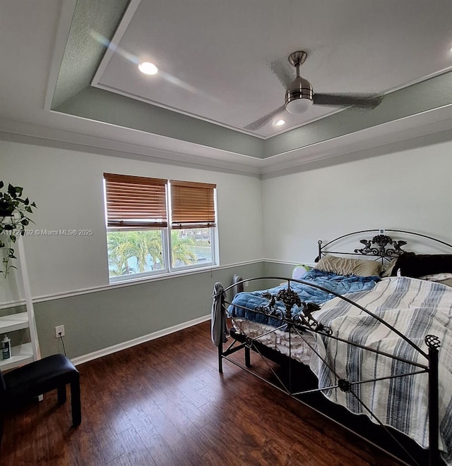 bedroom featuring a tray ceiling, wood finished floors, recessed lighting, baseboards, and ceiling fan