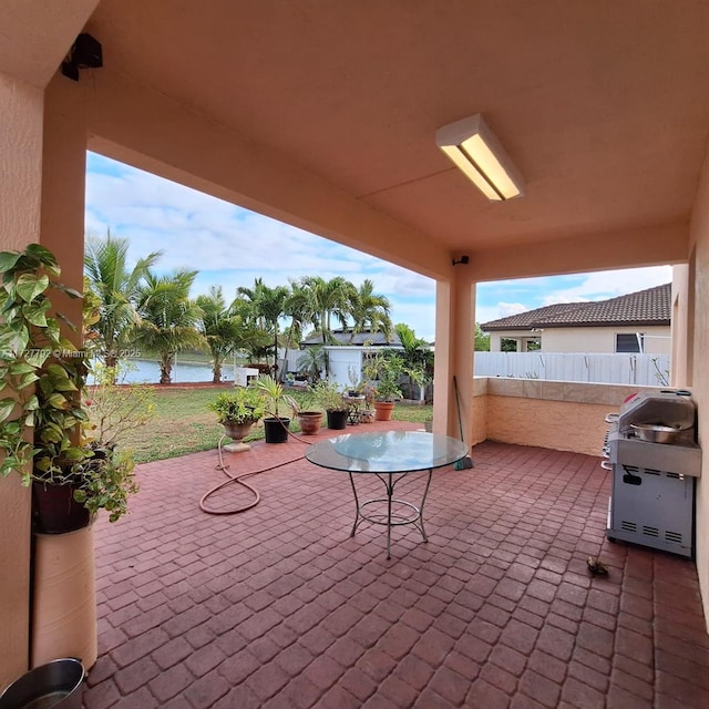 view of patio / terrace featuring a grill, fence, and a water view