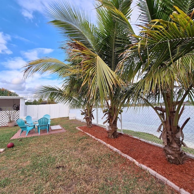 view of yard featuring a patio area, a water view, and fence