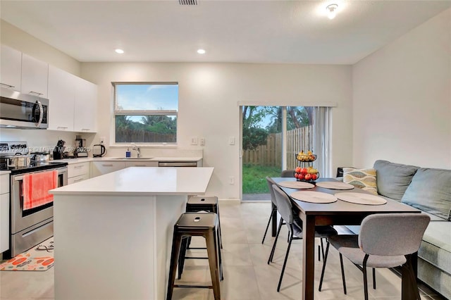 kitchen with sink, white cabinets, stainless steel appliances, and a kitchen island