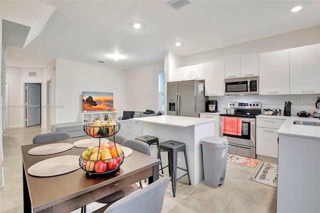 kitchen featuring appliances with stainless steel finishes, a center island, white cabinetry, sink, and a breakfast bar