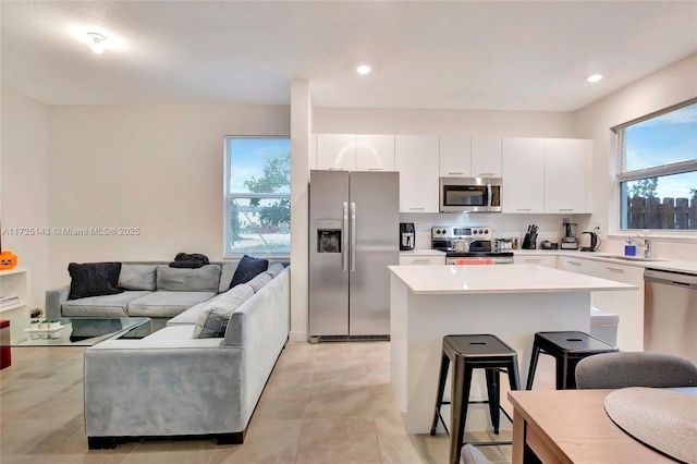 kitchen featuring white cabinets, appliances with stainless steel finishes, a kitchen breakfast bar, and a kitchen island