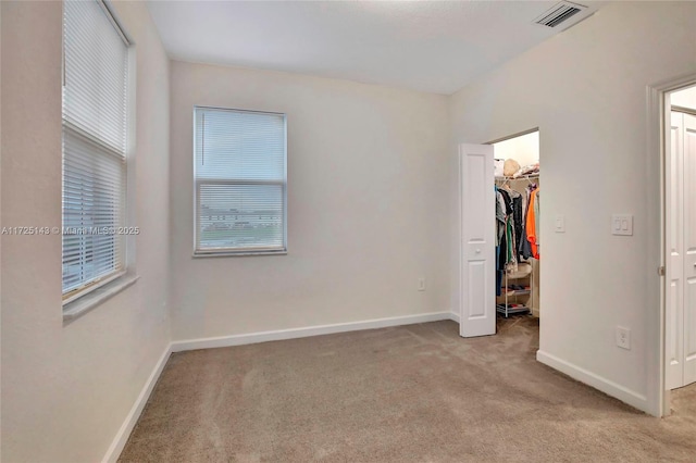 unfurnished bedroom with light carpet, a closet, and a spacious closet