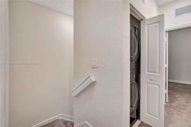 stairway with carpet floors and stacked washer and dryer