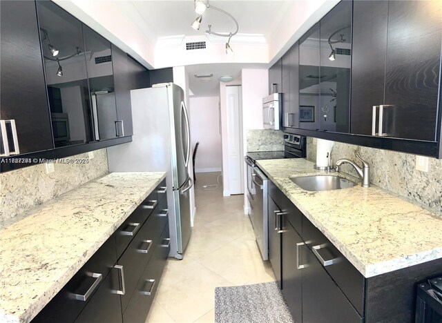 kitchen with light stone counters, stainless steel appliances, sink, and decorative backsplash