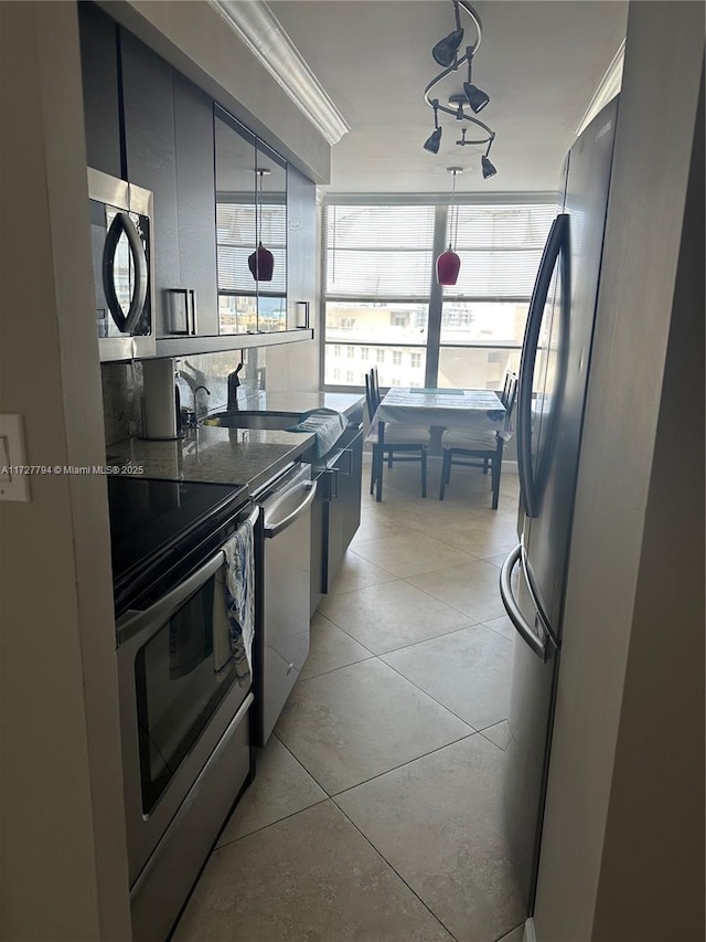 kitchen featuring stone counters, light tile patterned flooring, appliances with stainless steel finishes, decorative light fixtures, and crown molding