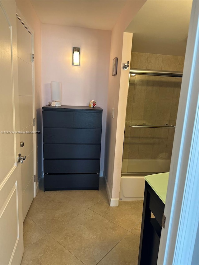 bathroom featuring tile patterned flooring, vanity, and bath / shower combo with glass door