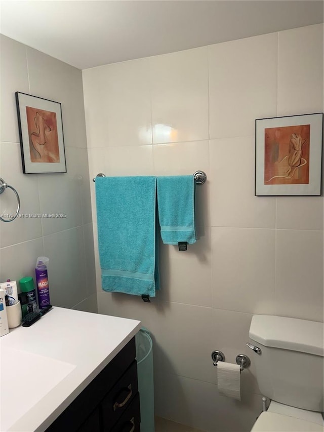 bathroom with vanity, toilet, and tile walls