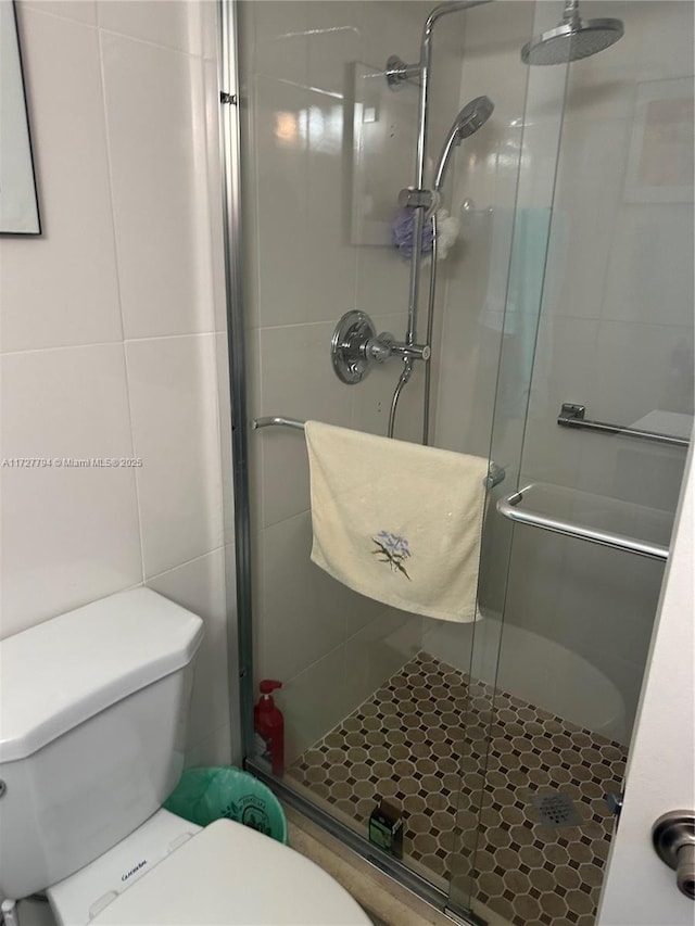 bathroom featuring an enclosed shower, toilet, and tile walls