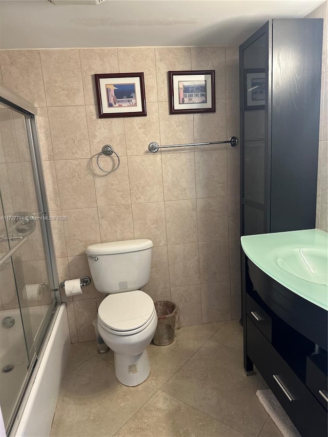 full bathroom with toilet, combined bath / shower with glass door, tile walls, vanity, and tile patterned flooring