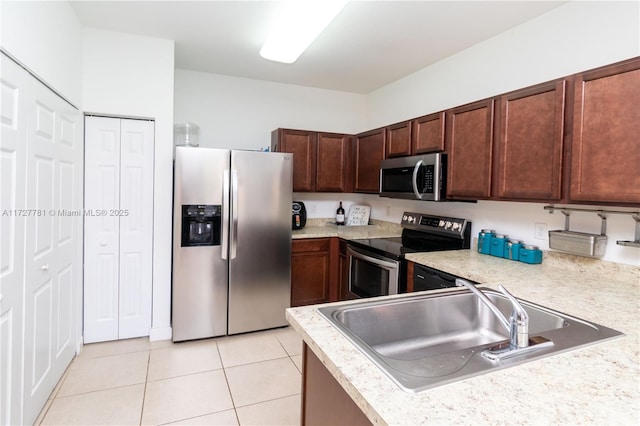 kitchen featuring light tile patterned floors, stainless steel appliances, dark brown cabinets, and sink