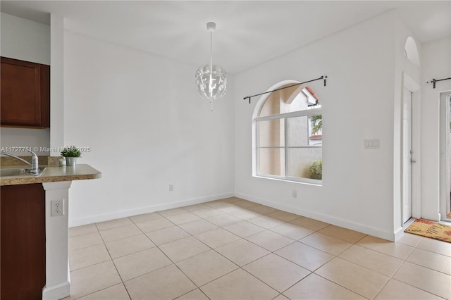 unfurnished dining area featuring light tile patterned floors, a chandelier, and sink