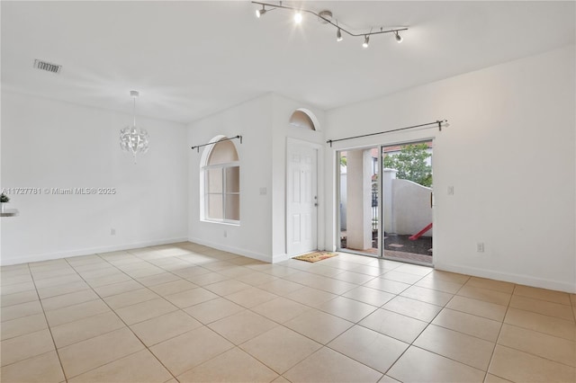 unfurnished room with a notable chandelier and light tile patterned flooring