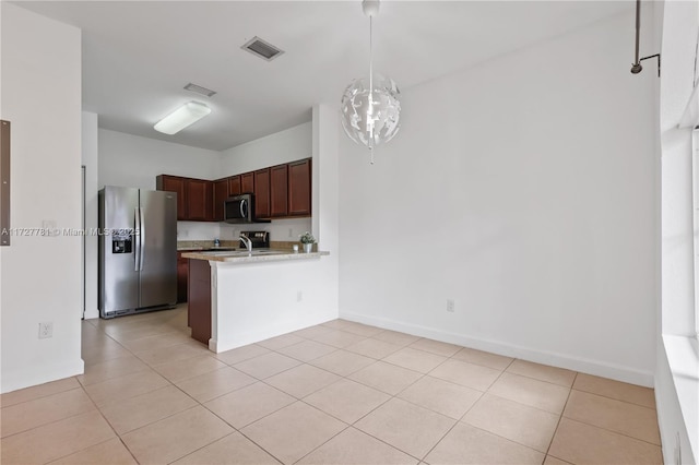 kitchen with light tile patterned floors, appliances with stainless steel finishes, pendant lighting, and dark brown cabinetry