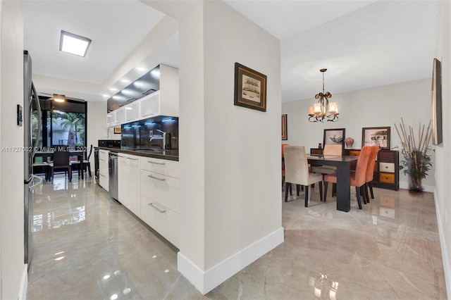 kitchen featuring pendant lighting, sink, white cabinetry, appliances with stainless steel finishes, and a chandelier