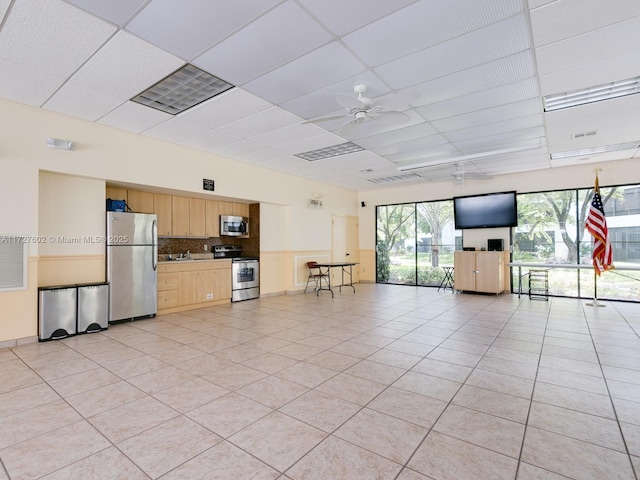 unfurnished living room with ceiling fan, light tile patterned floors, and a drop ceiling