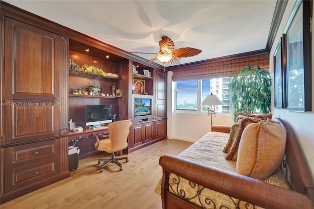 home office featuring light wood-type flooring, ceiling fan, ornamental molding, and built in desk