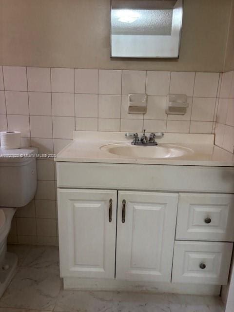 bathroom featuring toilet, vanity, and tile walls