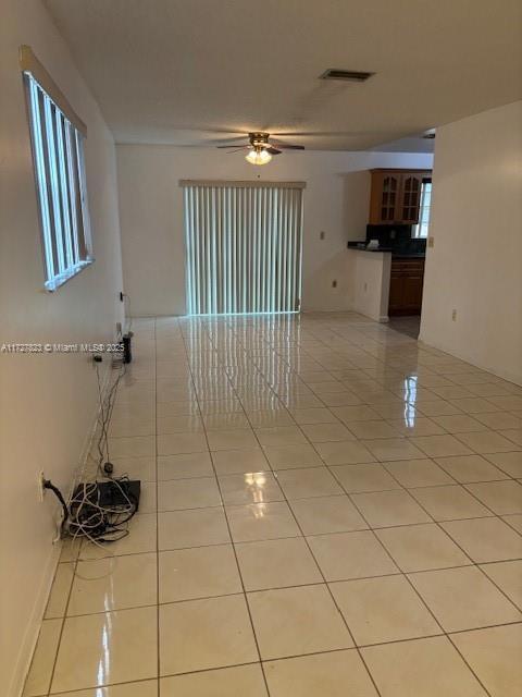 empty room with ceiling fan and light tile patterned floors