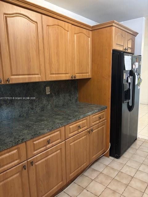 kitchen featuring light tile patterned floors, black refrigerator with ice dispenser, and decorative backsplash