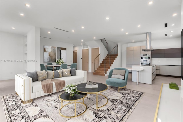 living room with recessed lighting, visible vents, finished concrete flooring, and stairs