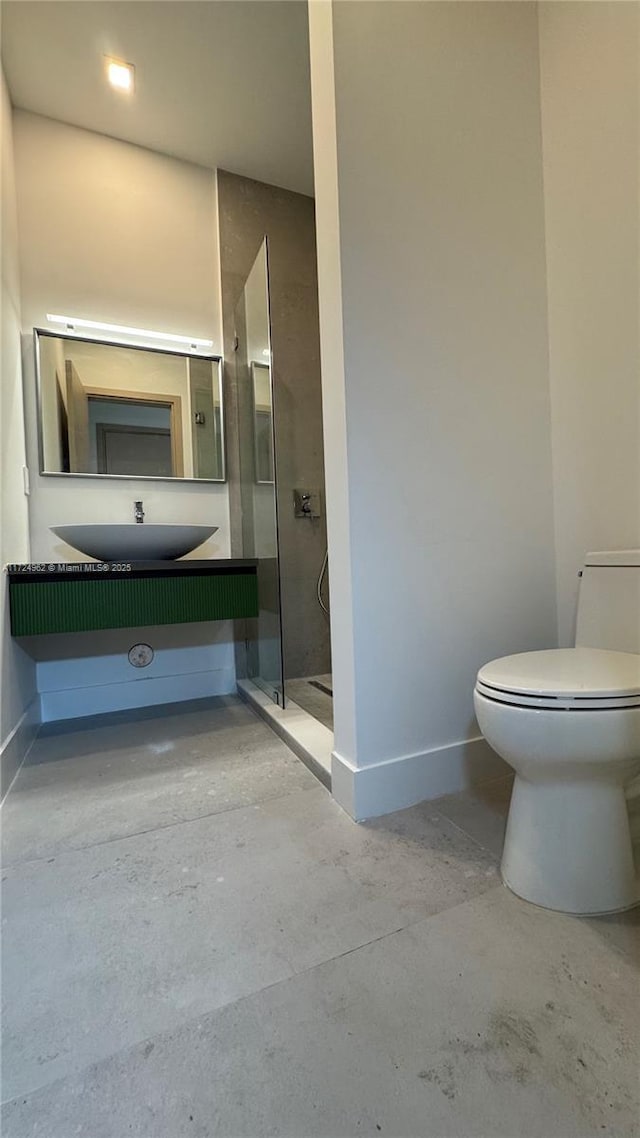 bathroom featuring toilet, vanity, a shower, and concrete floors