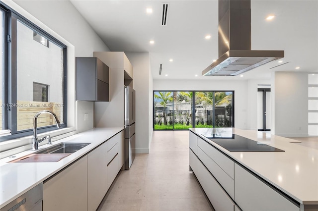 kitchen featuring island exhaust hood, a sink, visible vents, modern cabinets, and black electric stovetop