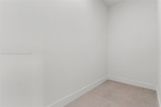 empty room featuring concrete flooring and baseboards