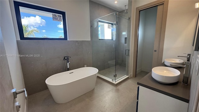 bathroom with separate shower and tub, vanity, and tile walls