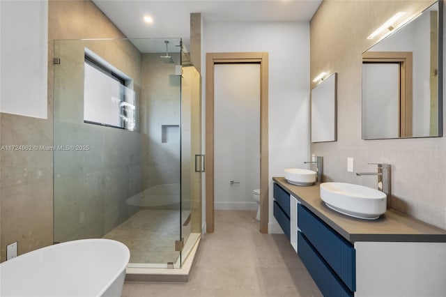 full bathroom featuring a freestanding tub, toilet, a stall shower, and a sink