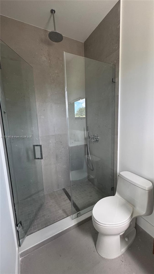 bathroom with toilet and a shower with door