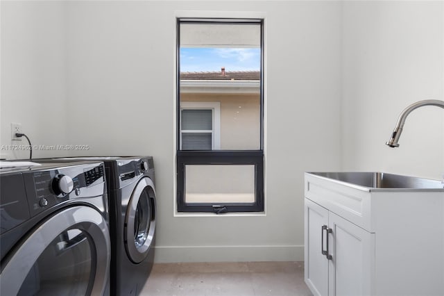 washroom featuring baseboards, washer and clothes dryer, a sink, and cabinet space