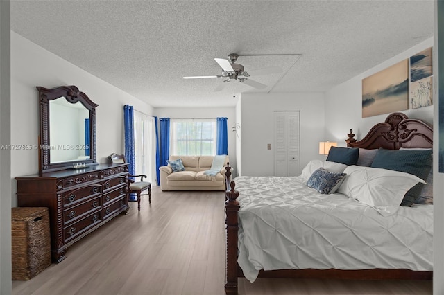 bedroom featuring a textured ceiling, ceiling fan, a closet, and light hardwood / wood-style floors