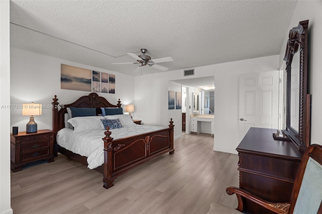 bedroom with ceiling fan, light hardwood / wood-style flooring, ensuite bathroom, and a textured ceiling