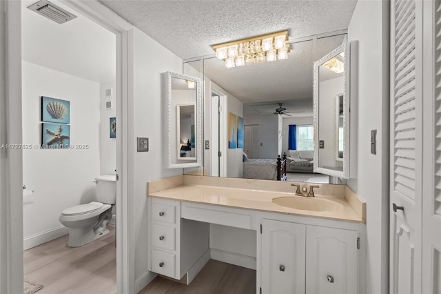 bathroom with a textured ceiling, ceiling fan, wood-type flooring, and vanity