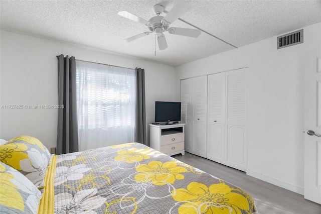 bedroom featuring ceiling fan, light hardwood / wood-style floors, a textured ceiling, and a closet