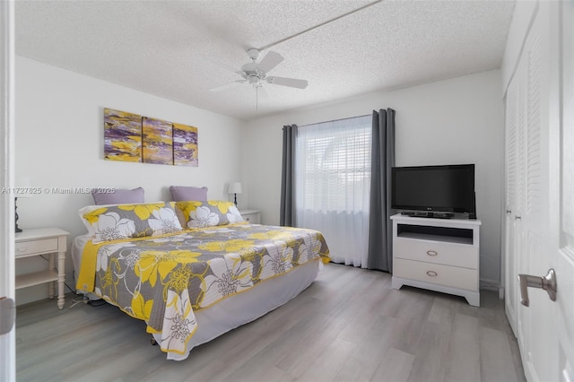 bedroom featuring a textured ceiling, ceiling fan, a closet, and light wood-type flooring