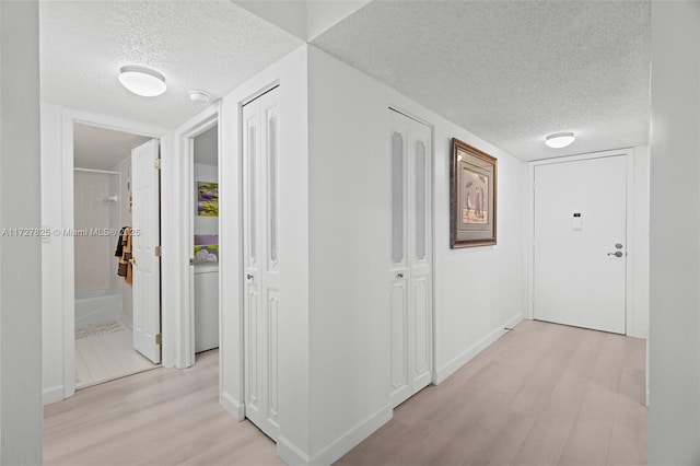 hall featuring a textured ceiling and light hardwood / wood-style floors