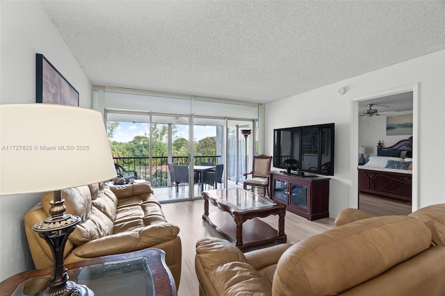 living room featuring a textured ceiling, ceiling fan, and light wood-type flooring