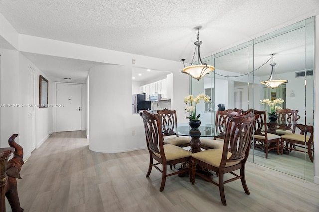 dining room featuring a textured ceiling and light hardwood / wood-style flooring