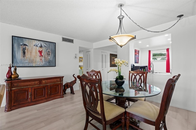 dining room featuring a textured ceiling and light hardwood / wood-style flooring