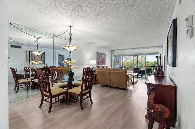 dining area featuring wood-type flooring and a textured ceiling