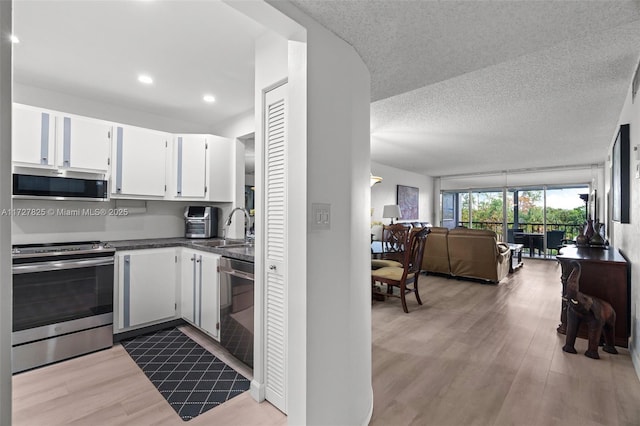 kitchen with a textured ceiling, white cabinetry, stainless steel appliances, light hardwood / wood-style floors, and sink