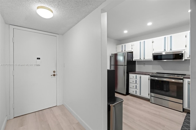 kitchen with white cabinetry, light hardwood / wood-style flooring, stainless steel appliances, and a textured ceiling