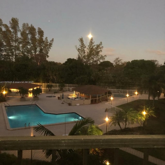 pool at dusk featuring a patio