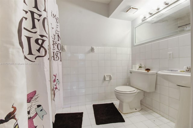 bathroom with tile walls, tile patterned floors, toilet, and a shower with shower curtain