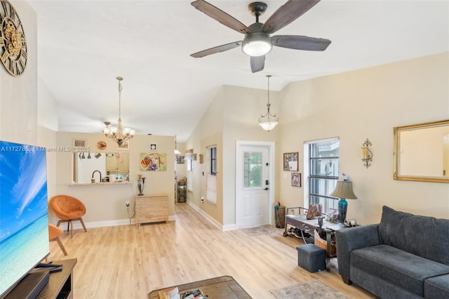 living room with ceiling fan with notable chandelier, light hardwood / wood-style flooring, and lofted ceiling