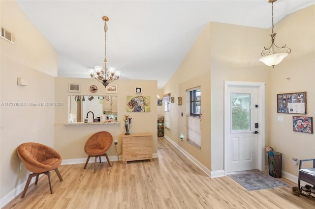 interior space featuring sink, light hardwood / wood-style flooring, an inviting chandelier, and vaulted ceiling