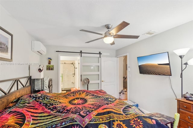 bedroom featuring a wall mounted air conditioner, ensuite bath, ceiling fan, and a barn door