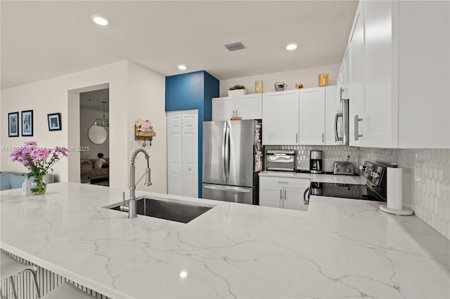 kitchen with sink, white cabinetry, light stone countertops, and stainless steel appliances